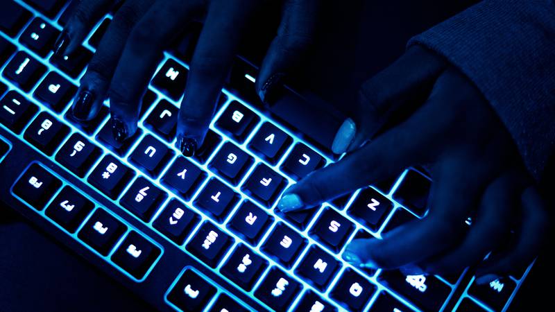 pessoa digitando no escuro com teclado iluminado