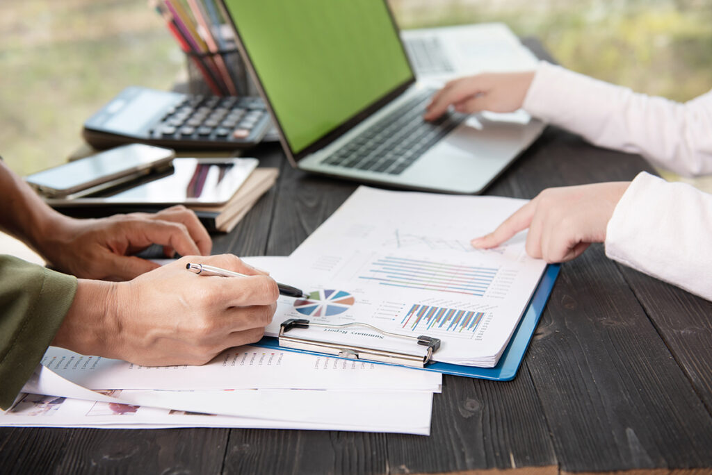 personas trabajando con computador y documentos en papel